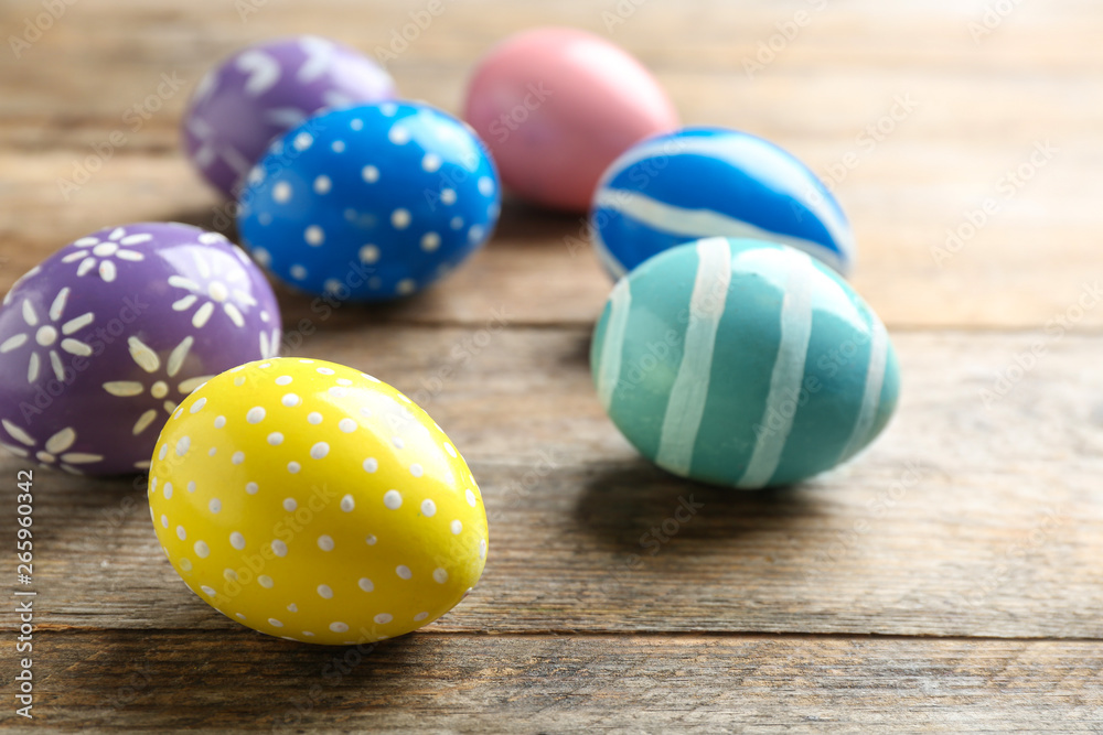 Fototapeta premium Painted Easter eggs on wooden table, space for text