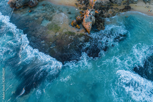 Looking down at waves crushing over rocks - aerial view