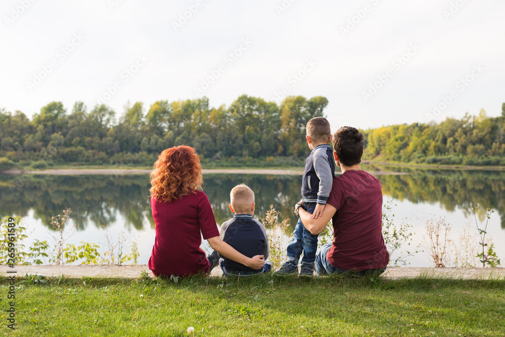 Childhood and nature concept - Family with little sons sitting on the green grass Childhood and nature concept - Family with little sons sitting on the green grass
