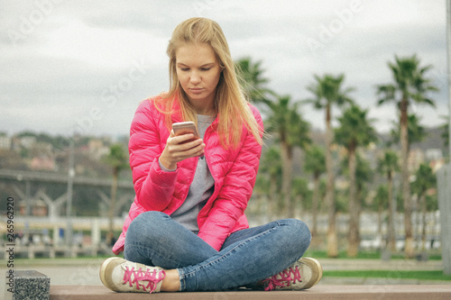 Portrait of beautiful blond girl posing for photo at the park with palm tree