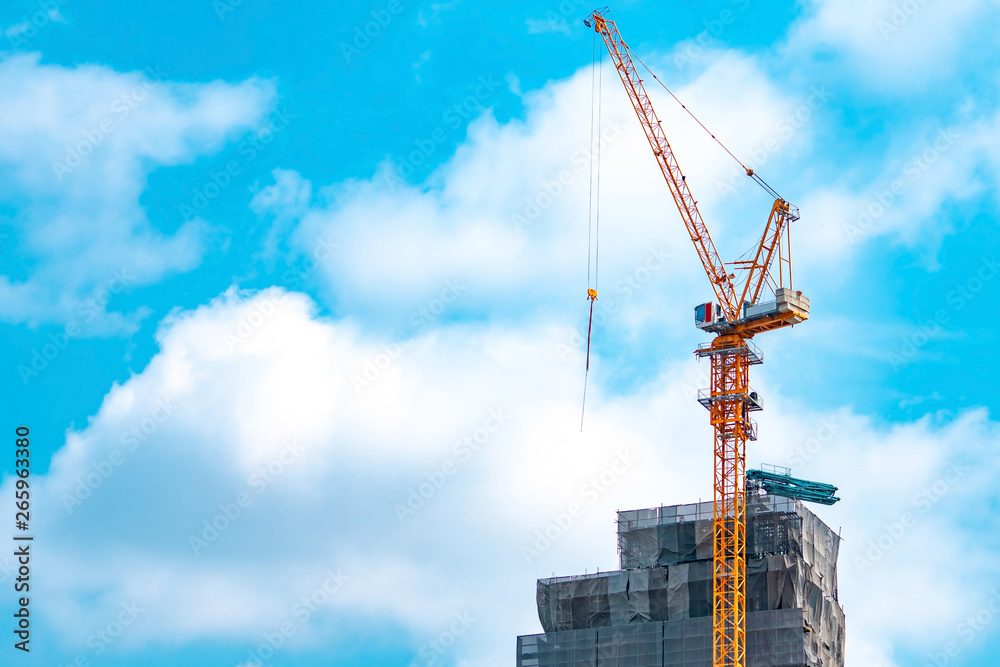 Construction site with crane and building. Real estate industry. Crane use reel lift up equipment in construction site. Building made of steel and concrete. Crane work against blue sky and white cloud Construction site with crane and building. Real estate industry. Crane use reel lift up equipment in construction site. Building made of steel and concrete. Crane work against blue sky and white cloud