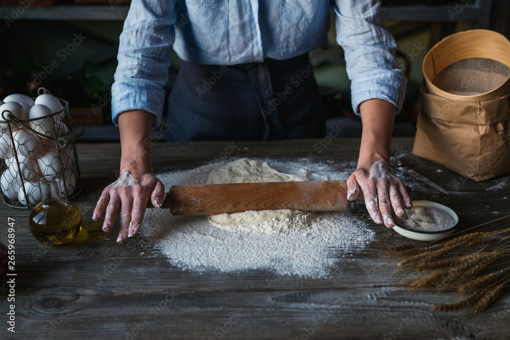Homemade raw pastry on a wooden table on a rustic wooden surface with a rolling pin, flour, butter, wheat spikelets. Homemade raw pastry on a wooden table on a rustic wooden surface with a rolling pin, flour, butter, wheat spikelets.