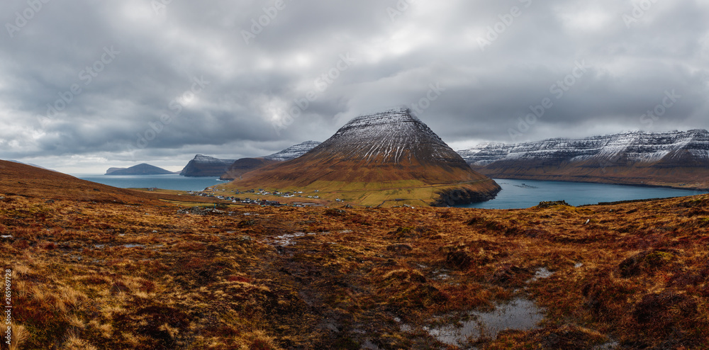 Panoramic view from Kap Enniberg to the small village Viðareiði, its fjords, snow-covered mountains and dramatic sky (Faroe Islands, Denmark, Europe)