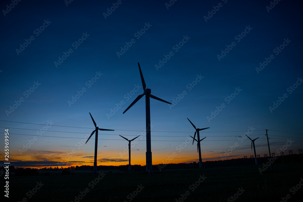 Power generators of windmills at shadow sunset - Wind turbine on field at sunset