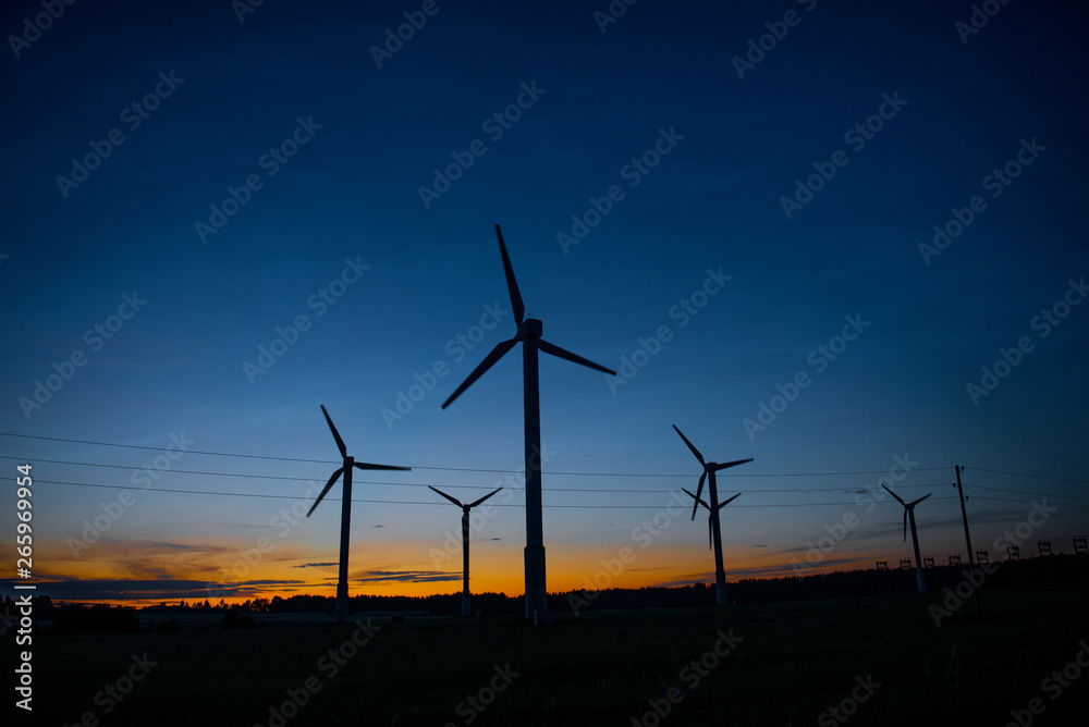 Obraz premium Power generators of windmills at shadow sunset - Wind turbine on field at sunset