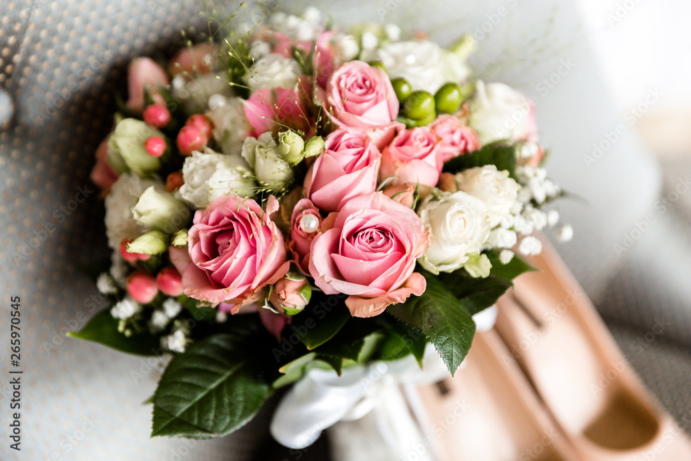 Obraz premium Wedding bouquet of white and pink roses on a blurred background of the bride's shoes
