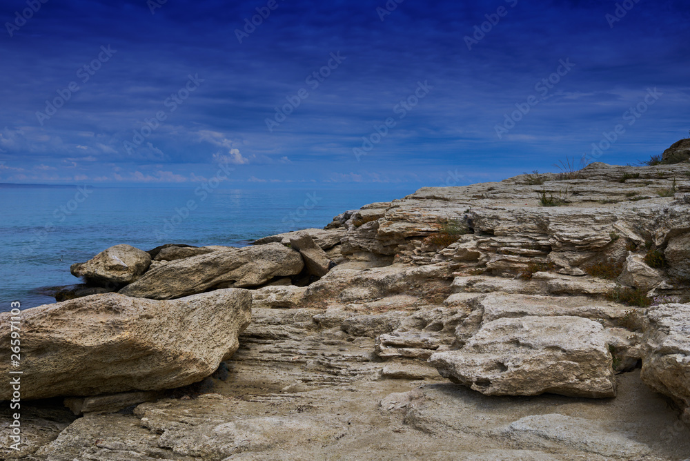 Panorama landscape scenic view of isolated deserted rocky beach with blue turquoise sea water and sky with white clouds and mountain background on beautiful and colorful Mallorca island in Spain. Panorama landscape scenic view of isolated deserted rocky beach with blue turquoise sea water and sky with white clouds and mountain background on beautiful and colorful Mallorca island in Spain.