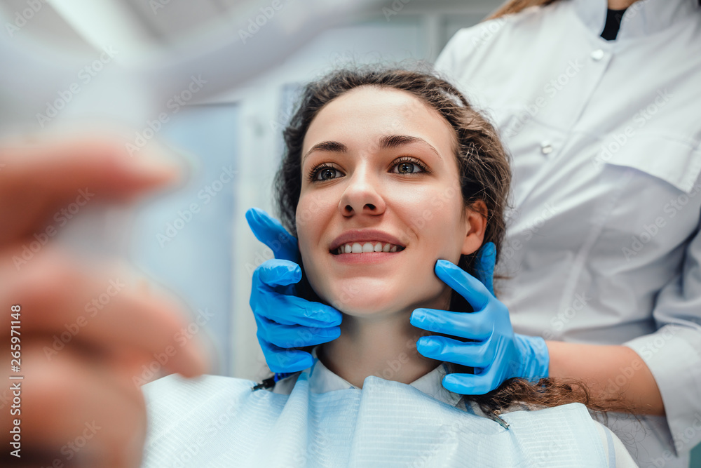 Healthcare and medicine concept.Happy woman patient looking in the mirror at the teeth, sitting in the dental chair. selective focus. Healthcare and medicine concept.Happy woman patient looking in the mirror at the teeth, sitting in the dental chair. selective focus.