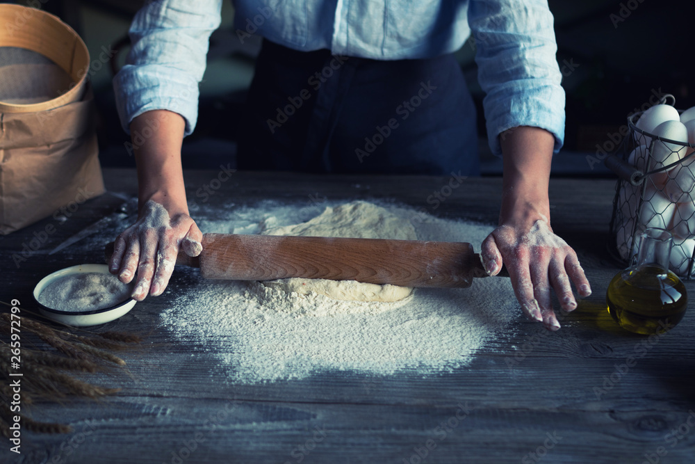 Baking concept. Working woman prepares pastry by himself, kneads dough on wooden counter with flour and rolling pin. Female cook bakes bread or delicious bun. Baking concept. Working woman prepares pastry by himself, kneads dough on wooden counter with flour and rolling pin. Female cook bakes bread or delicious bun.