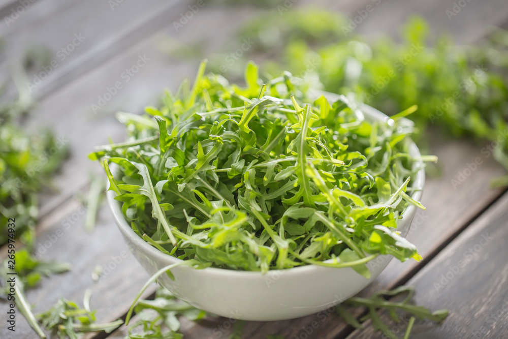 Fresh arugula salad in white dish on wooden table Fresh arugula salad in white dish on wooden table