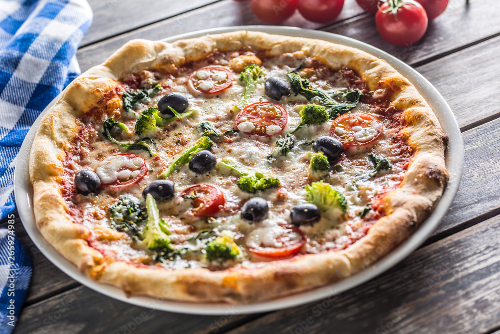Irtalian pizza with broccoli spinach tomatoes olives and mozzarela or parmesan cheese. Mediterranean vegetarian meal