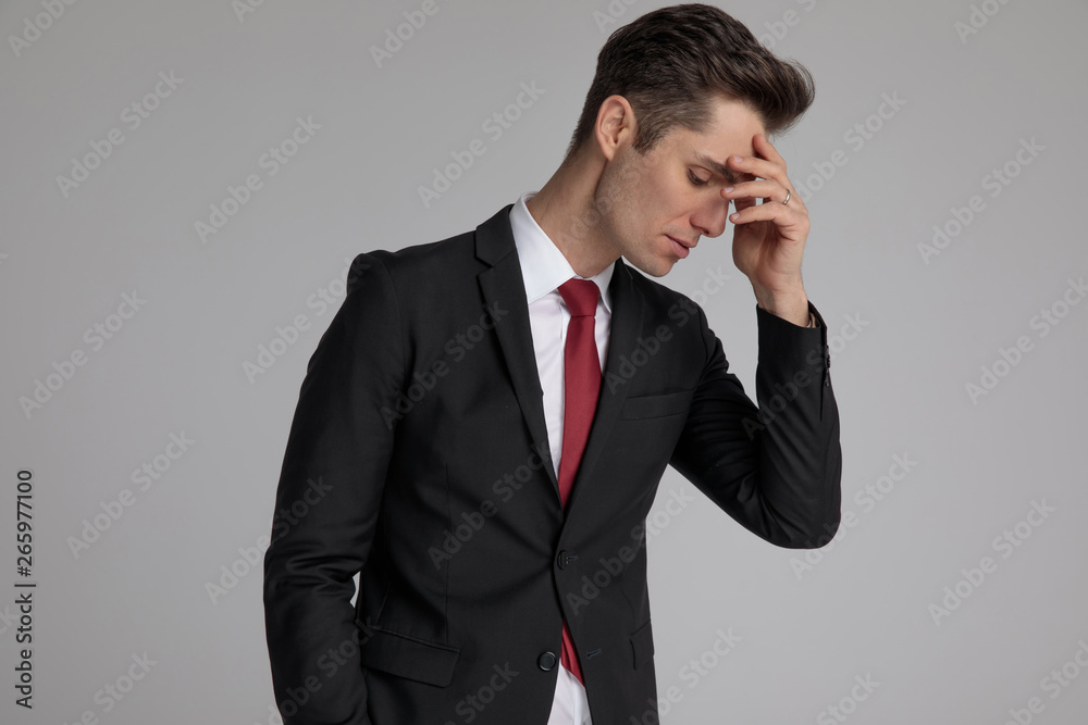 caucasian man looking down with hand at forehead caucasian man looking down with hand at forehead