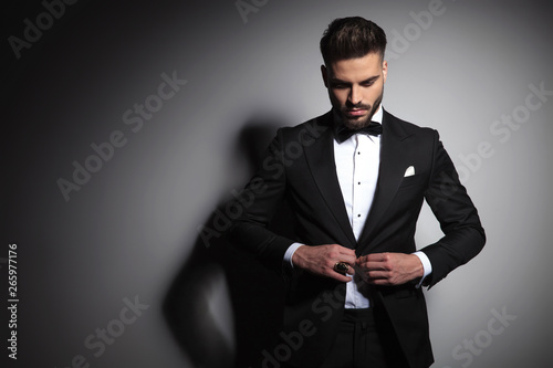 Fototapeta caucasian man in black tuxedo buttoning his suit