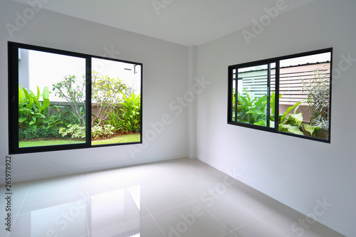 slide glass window and clean tile floor in empty room with small garden landscaping outside a new house
