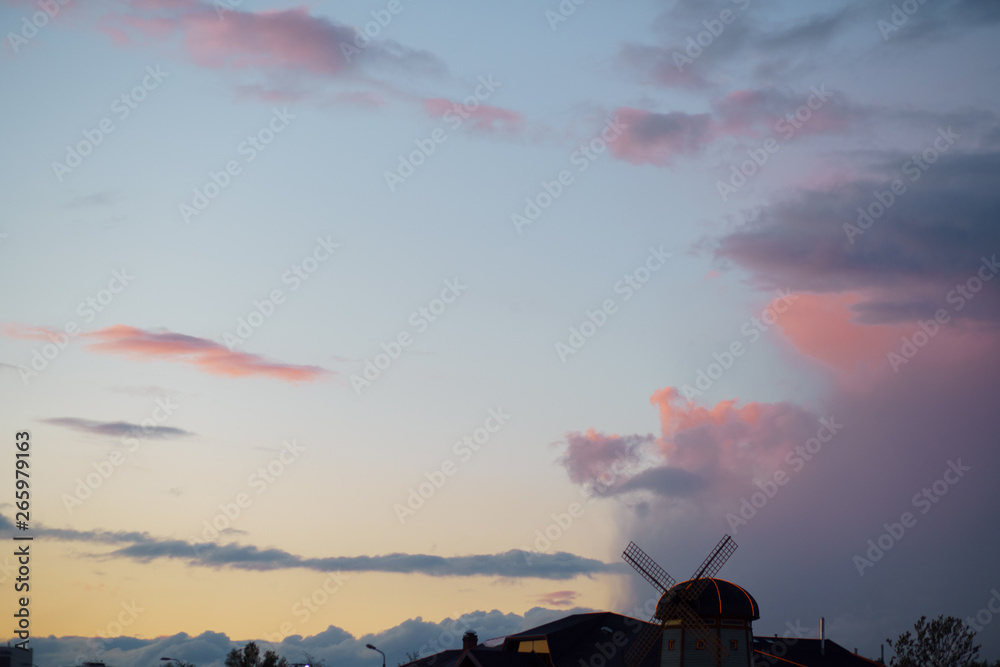 Pink vivid sunset with a mill in the background - Rainy clouds taking over in this beautiful landscape scenery of our nature