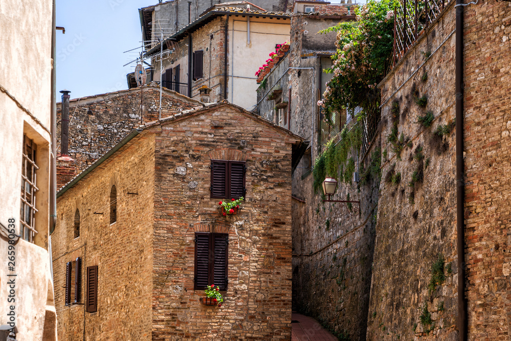 Beautiful view of cozy street of San Gimignano and Old Town of medieval town in the sunny day. Tuscany, Italy.