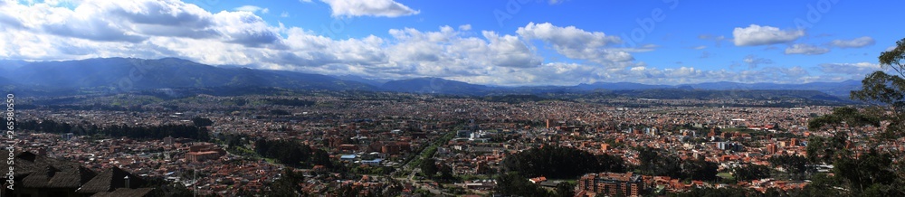 Panoramic view of a large city, Cuenca, with mountains and clouds in the background