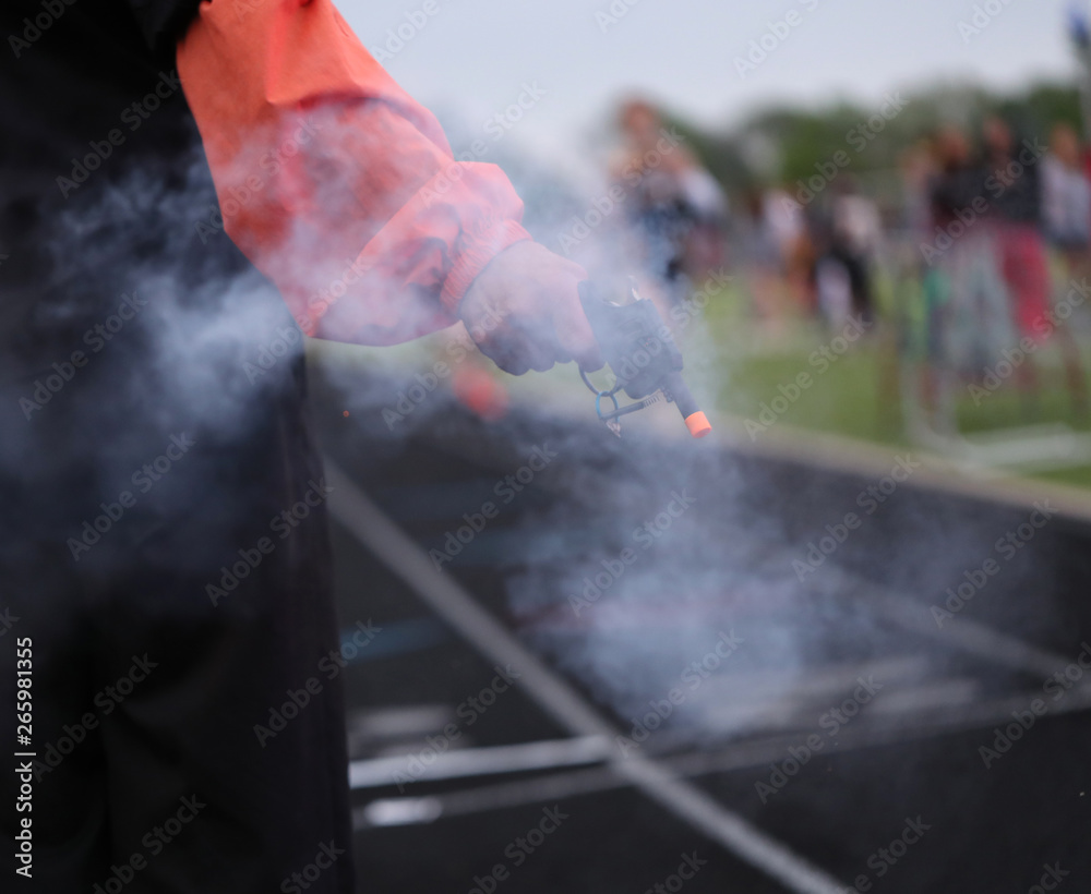 Obraz premium A starter gun signals the final lap in a high school track meet