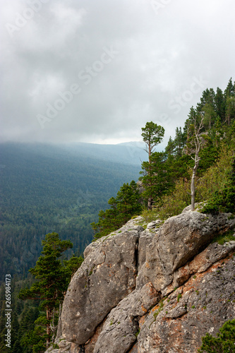 View of the rock near the checkpoint in the Lago-Naki Caucasian Reserve. Green trees on a summer day and mountains in the clouds in the background. Western Caucasus  Krasnodar Territory  Russia