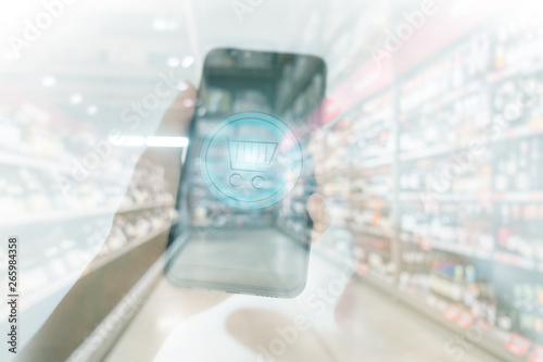 Shopping basket on a mobile phone screen. Woman Hand holding mobile phone on Supermarket blur background