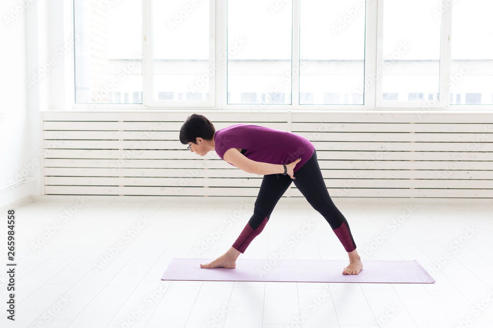 Yoga, people concept - a middle-aged woman doing a yoga in the gym