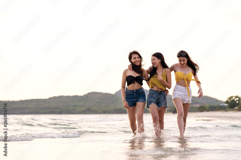 Full length of three young attractive asian girl friends group walk, talk and laughing fun on sea beach in summer bikini wearing. Beauty young asian women smiling together in vacation leisure time. Full length of three young attractive asian girl friends group walk, talk and laughing fun on sea beach in summer bikini wearing. Beauty young asian women smiling together in vacation leisure time.