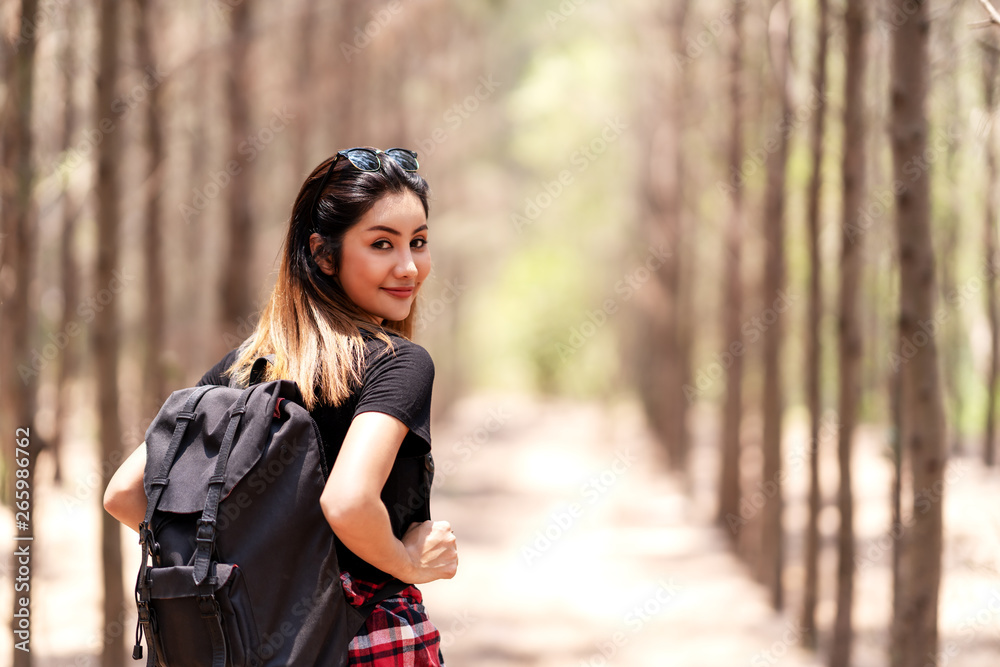 Attractive happy asian teenage student smile to camera enjoy travel in outdoor on sunny day. Asian woman backpacker in concept of young adventure traveller. Sun protection in summer vacation.
