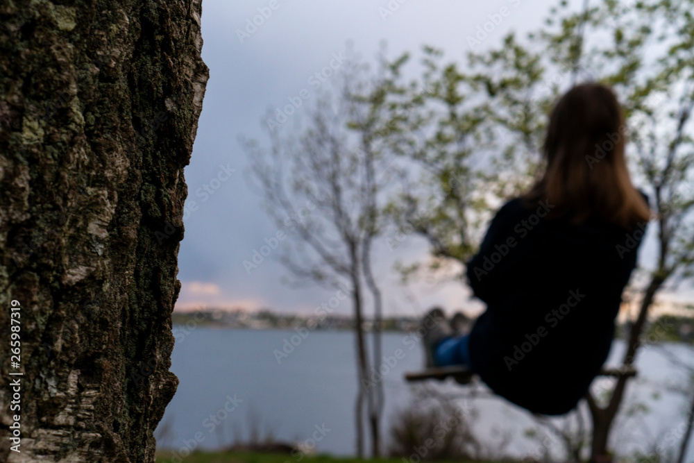 Girl swings under a tree looking out on the shore of Norway. Girl swings under a tree looking out on the shore of Norway.