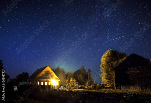 majestic milky Way and the shooting star above the village house in summer. A starry night sky. © shangarey