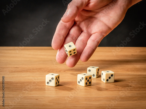 Hand throwing dice in front of a dark background.