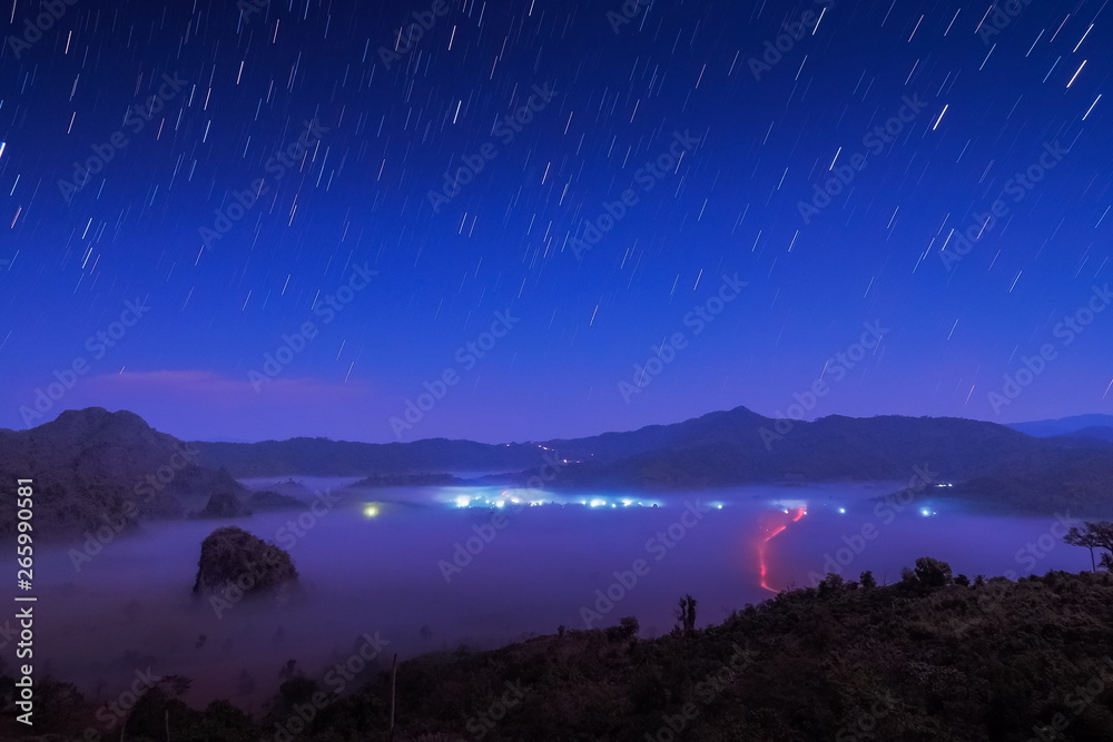 Mountain view scenic sea of fog in valley and the hills at night with stars in dark sky background, before sunrise at Photo Corner Phu Langka, Route 1148, Phayao, Thailand.