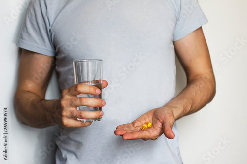  young  man holding a glass of water  and pills
