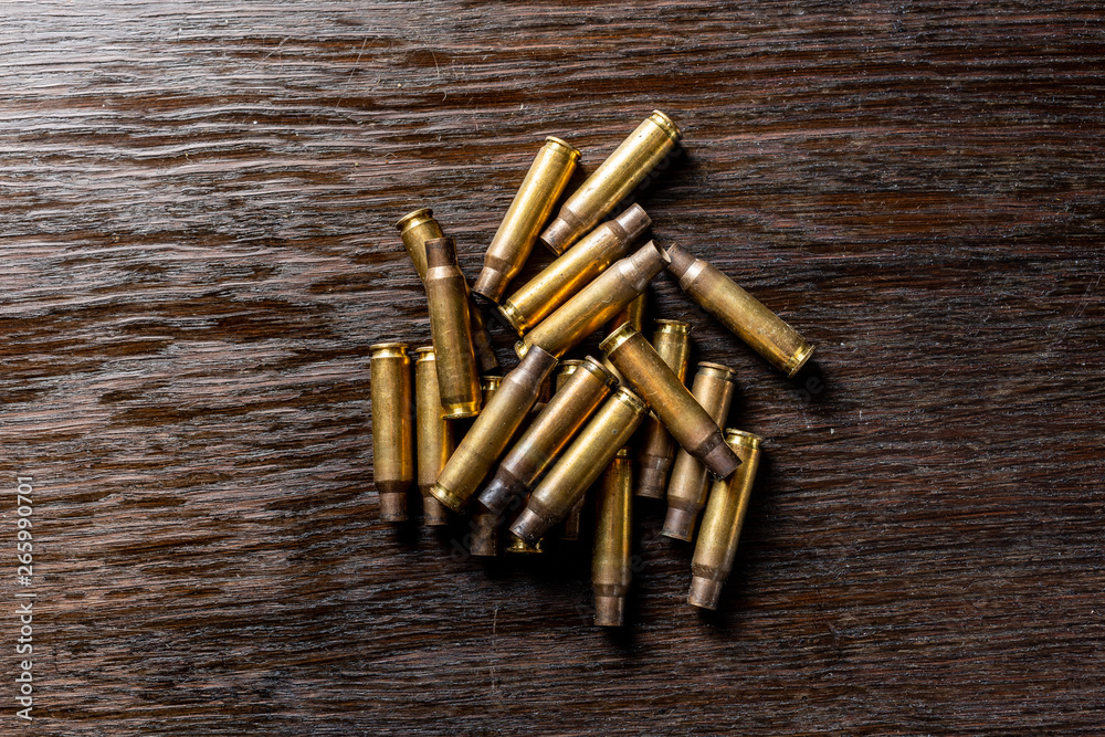 Empty bullet casings on a dark, wooden table. Empty bullet casings on a dark, wooden table.