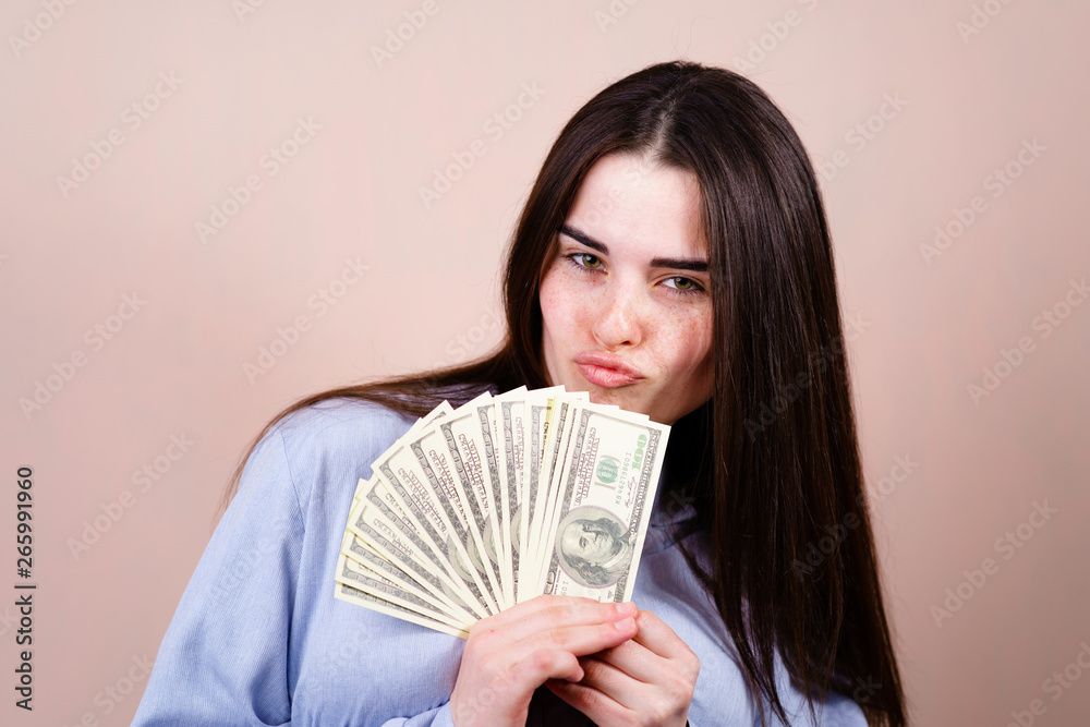 Savings, earning, money and banking, purchases and shopping. Beautiful young woman joyfully holding in her hand a lot of dollars
