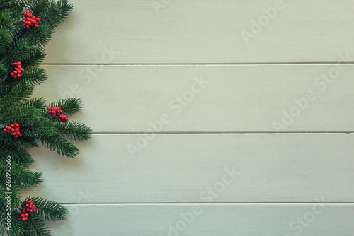 Christmas wooden background with fir branches and red berries. View with copy space.