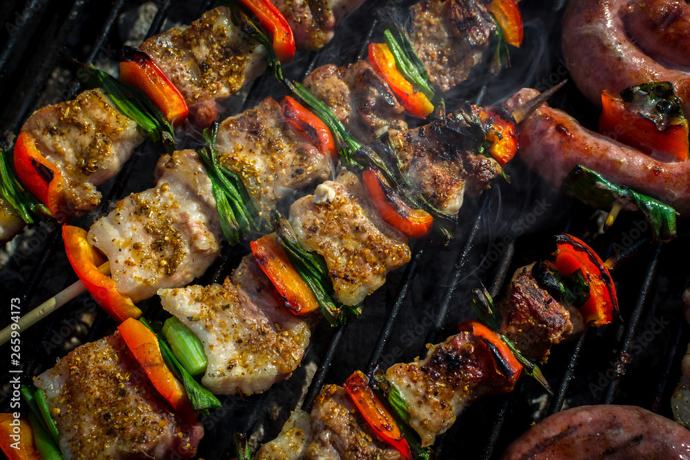 Close up pf delicious chicken breast on wooden skew with fresh vegetables, garlic, paprika fried on mangal barbeque grill and smoke Close up pf delicious chicken breast on wooden skew with fresh vegetables, garlic, paprika fried on mangal barbeque grill and smoke