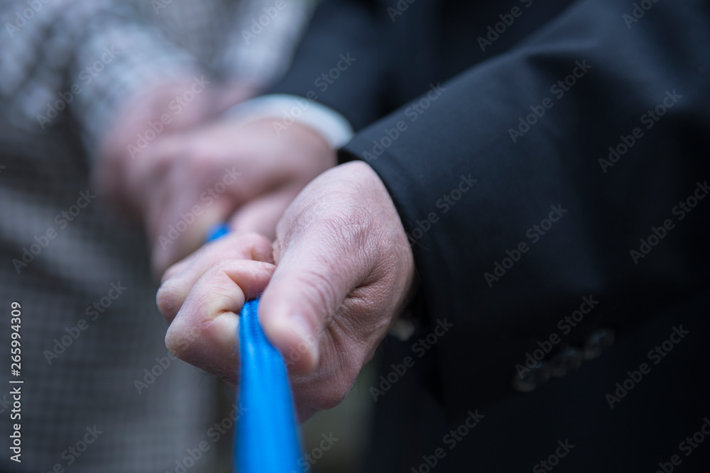 Pull together on a blue rope, human hands of male persons, business