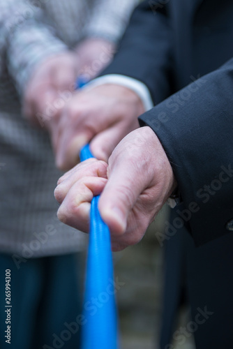 Pull together on a blue rope, human hands of male persons, business