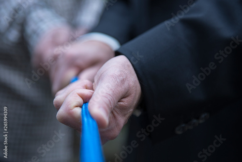 Pull together on a blue rope  human hands of male persons  business