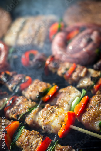 Close up pf delicious chicken breast on wooden skew with fresh vegetables, garlic, paprika fried on mangal barbeque grill and smoke