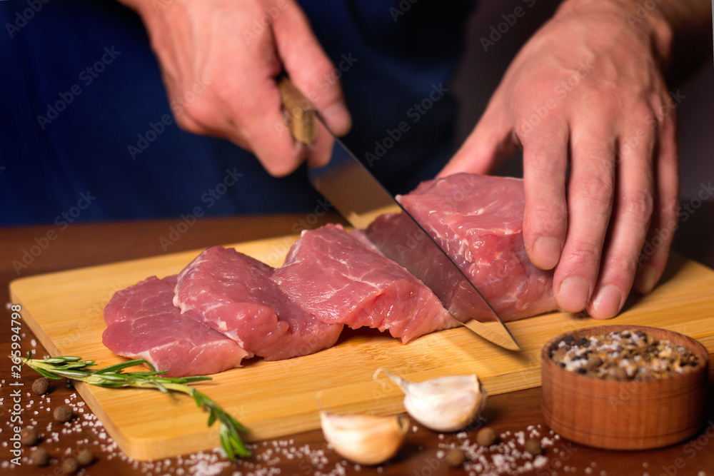 The butcher cuts a piece of pork on a cutting Board.