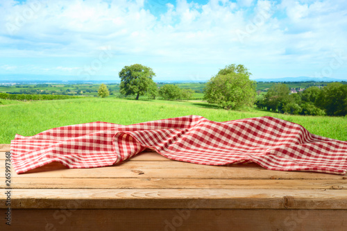 Empty wooden table with tablecloth over summer meadow background photo