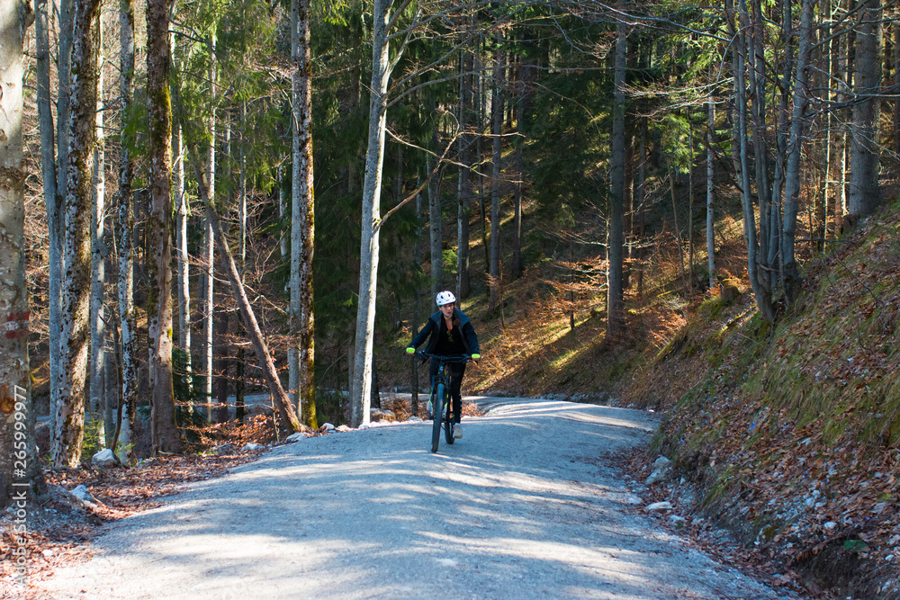 Obraz premium Junge freudige Frau fährt mit einem Mountainbike einen Steilen Berg hinauf in den Alpen
