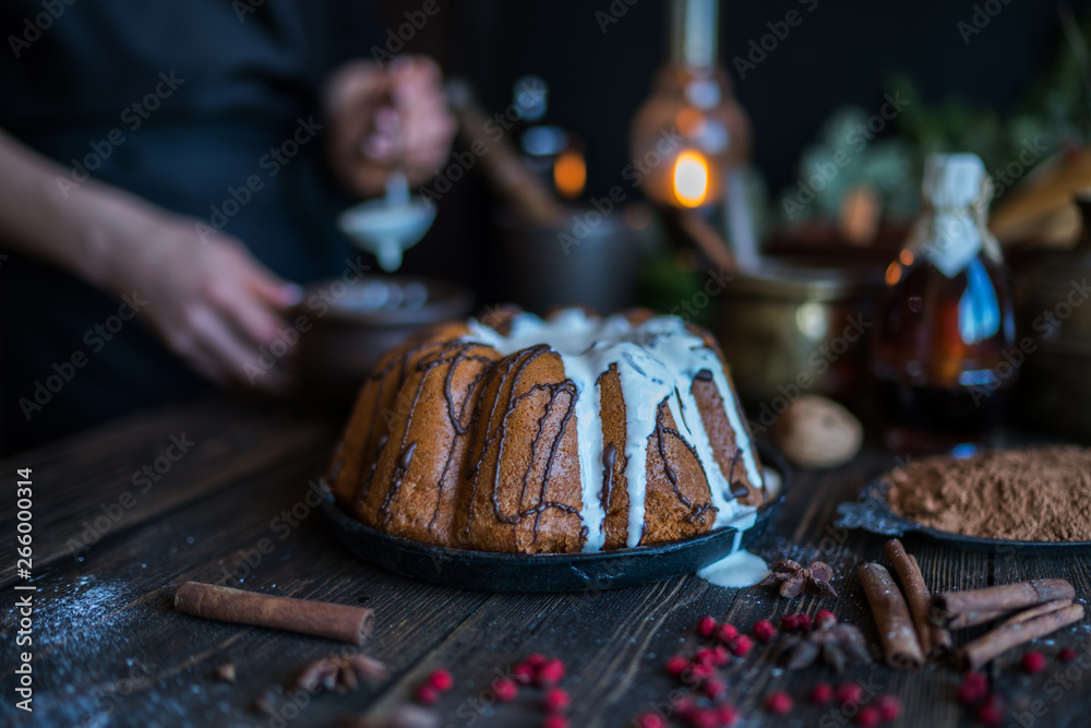 Holiday cake on wooden table with berry, spice and chocolate at rustic home kitchen. Christmas baking background. Ingredients for cooking on dark wooden background. Homemade festive food. Toned image