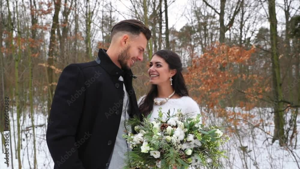 Newlyweds start smiling at each other on a snowy road during a winter wedding in nature. Newlyweds start smiling at each other on a snowy road during a winter wedding in nature.