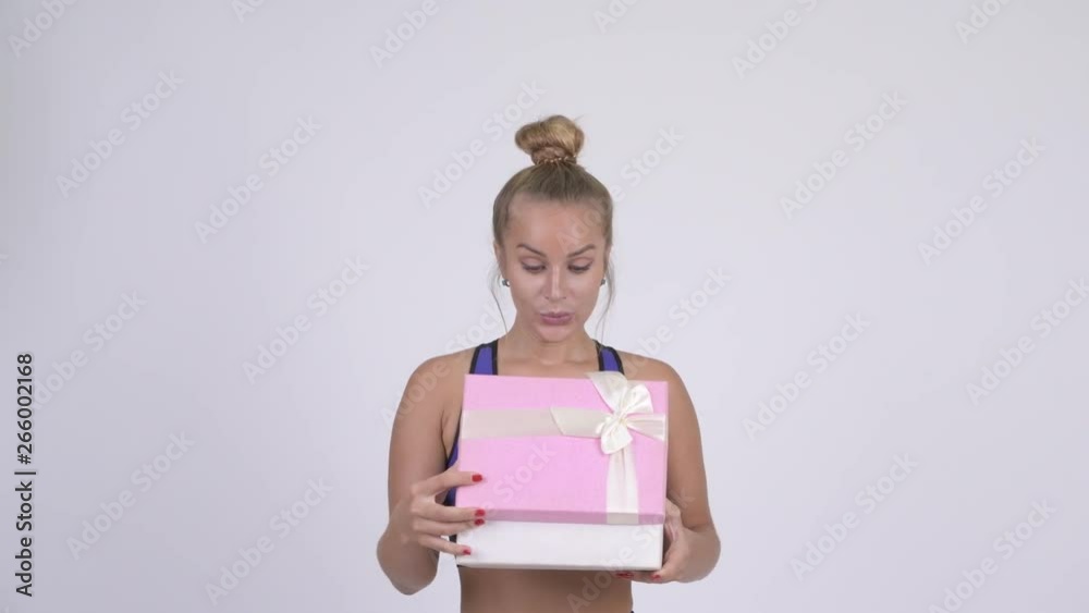 Happy young blonde woman looking surprised while opening gift box Happy young blonde woman looking surprised while opening gift box