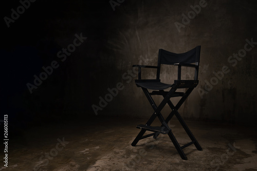 A black wooden chair stands in a photo studio against the background of an old  scratched concrete wall.