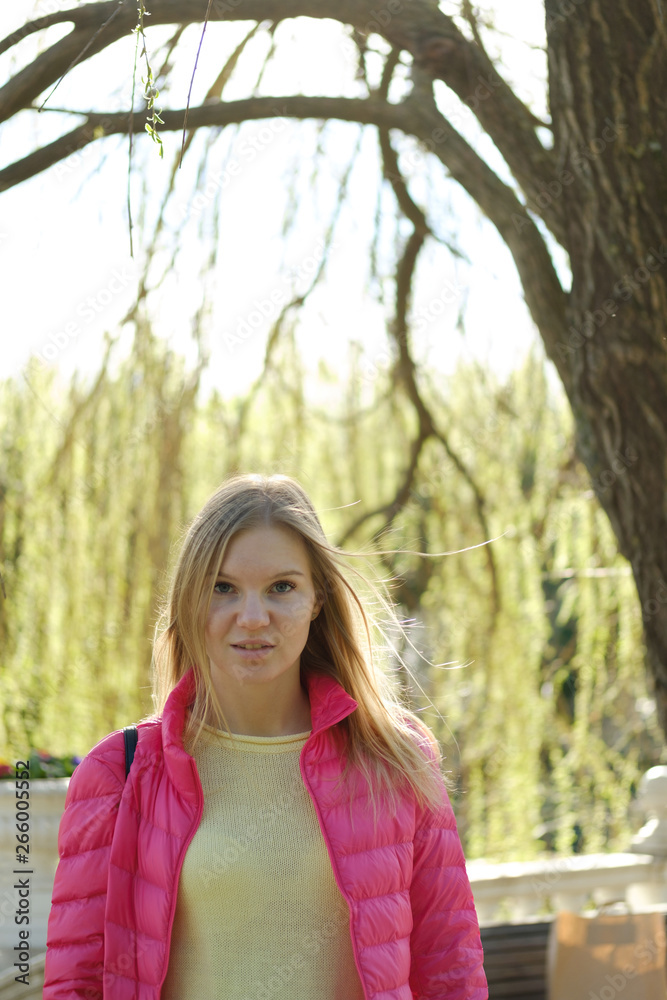 Beautiful blond girl posing for photo at the park with flowers