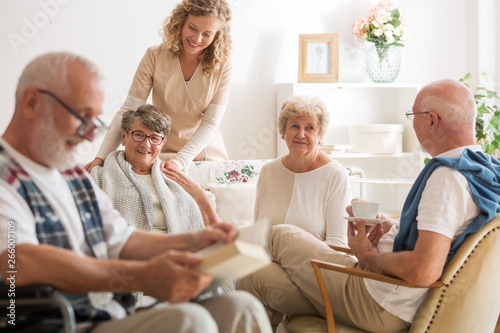 Group of senior friends sitting together at nursing home living room photo