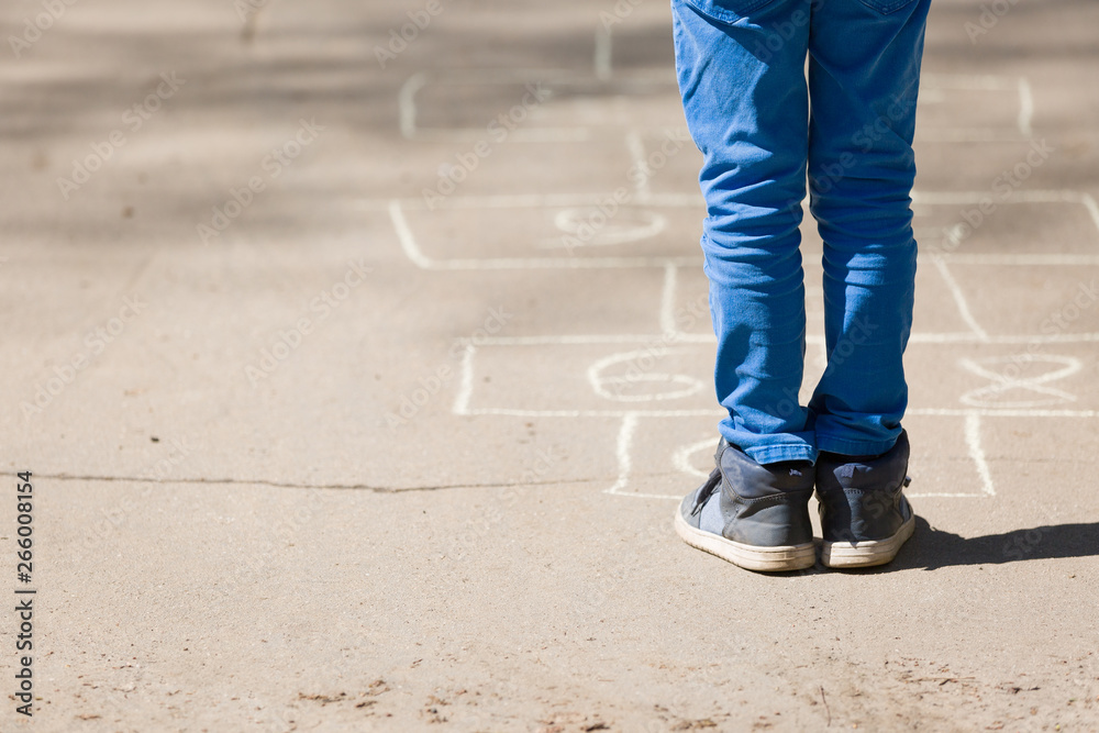 A little boy plays hopscotch on asphalt or pavement. Creative child, fun activity. Outdoor games. Early development A little boy plays hopscotch on asphalt or pavement. Creative child, fun activity. Outdoor games. Early development